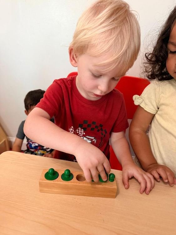 A boy practicing fine motor skills with a wooden peg board