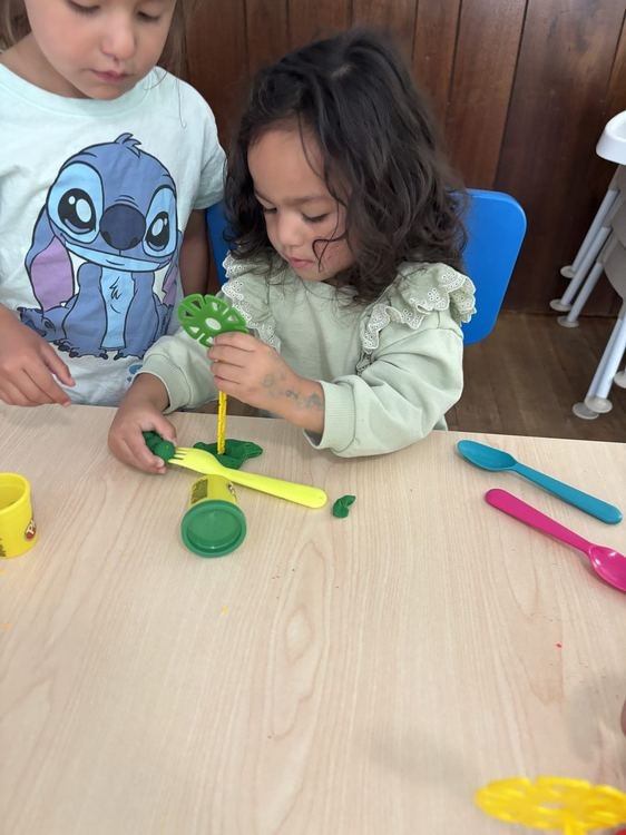 Two girls playing with green playdough together