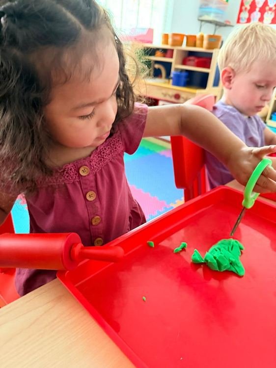 A girl playing with green playdough