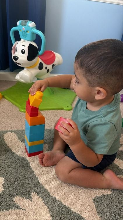 A toddler boy adding the final block to his tower