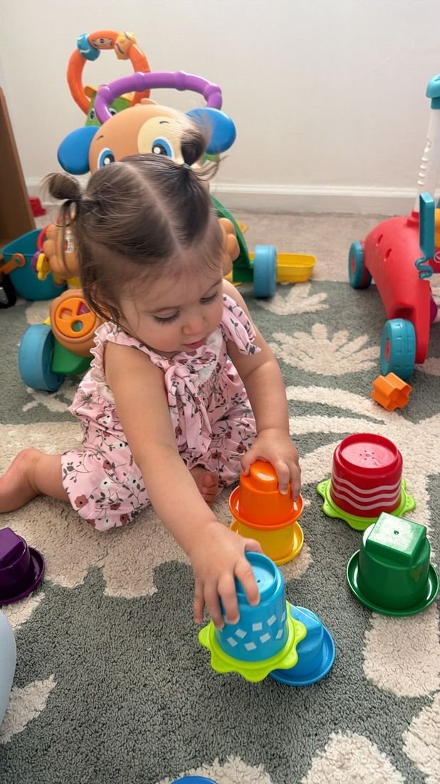 A toddler girl stacking colorful cups
