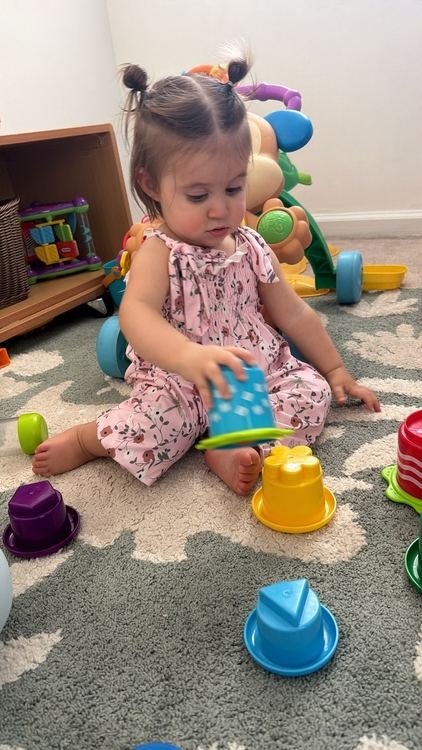 A toddler girl playing with a stacking cup
