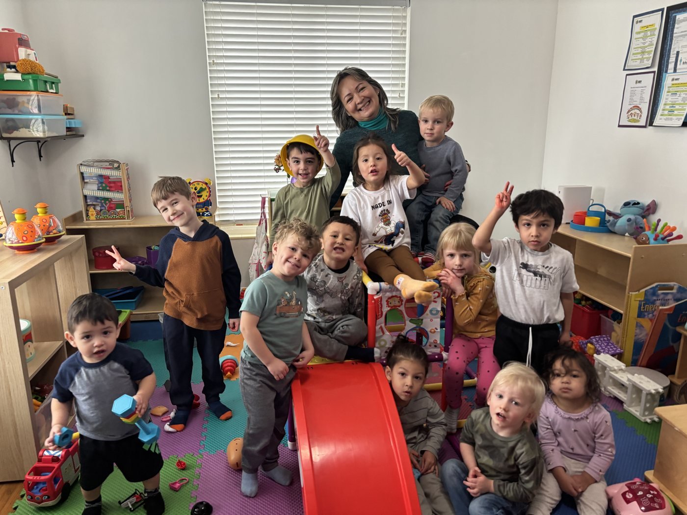 Elvira and the full group of children at Aby Early Learning Center smiling together in the classroom